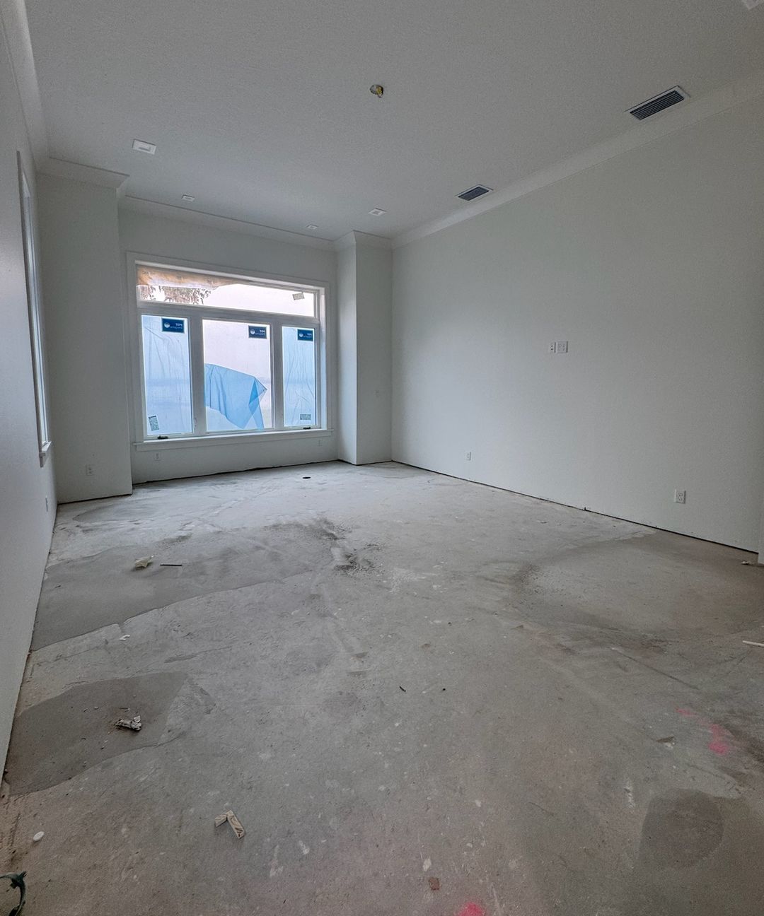 A bedroom on day one: a bare concrete slab under a wide window.