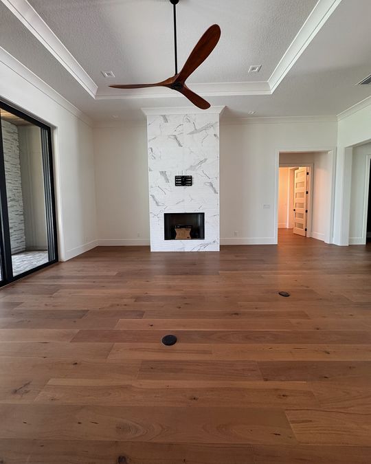 A great room with a marble fireplace and a wide-plank hardwood floor.