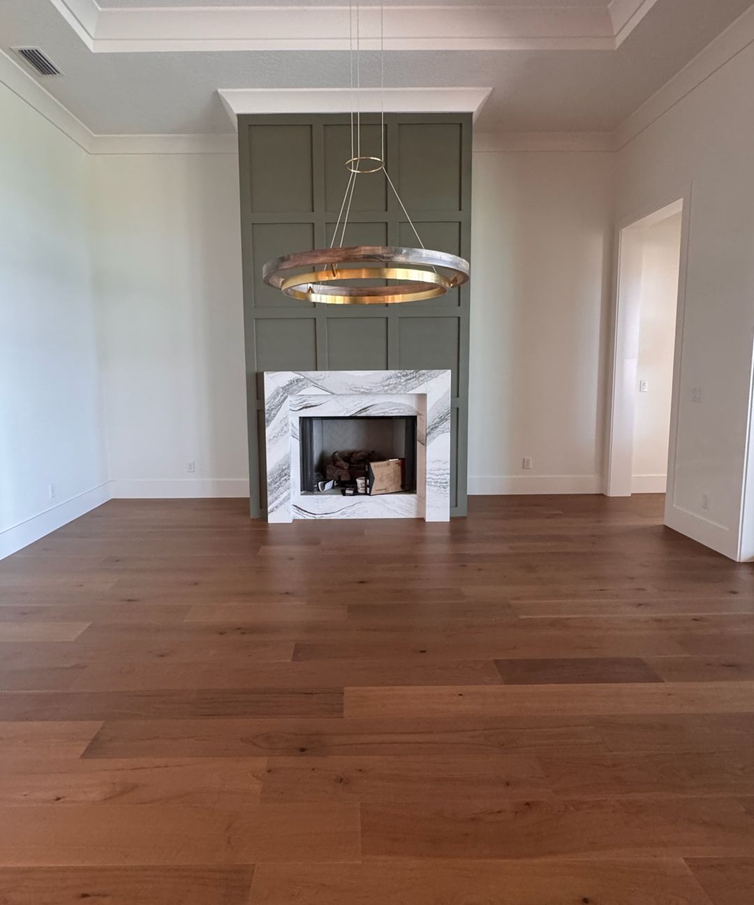 The same living room when done, with a wide-plank hardwood floor in front of the fireplace.