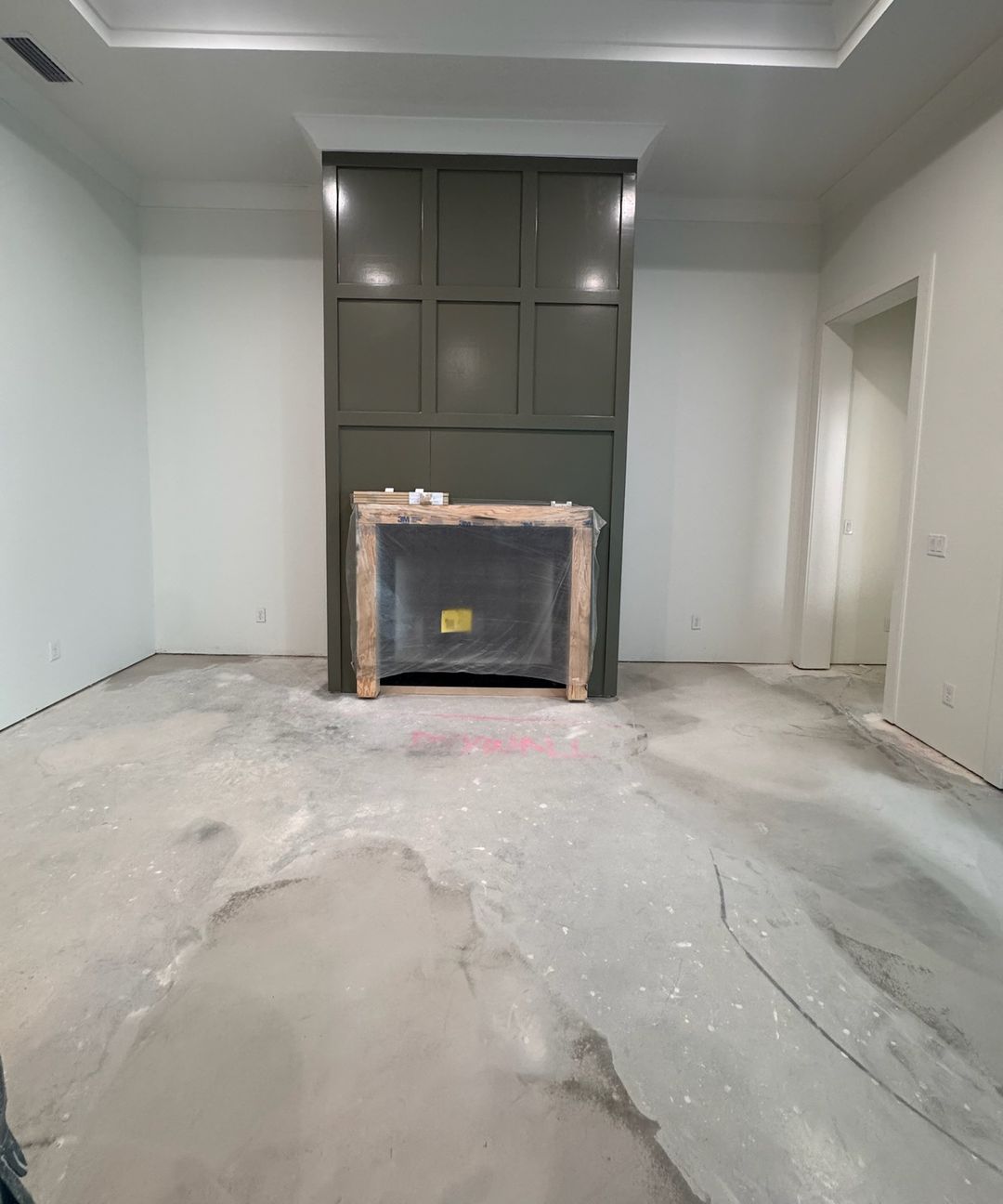 A living room on day one: a bare concrete slab in front of a wrapped fireplace.